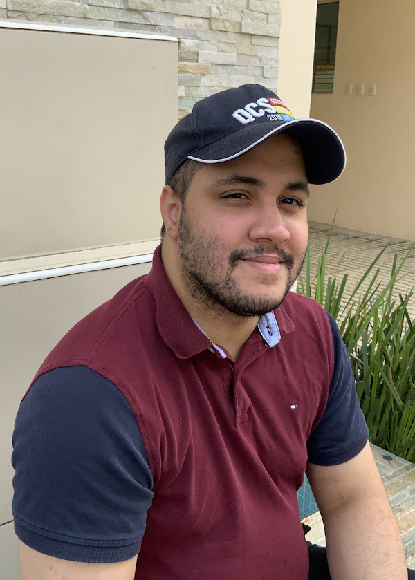 Fabio wearing a cap and a red shirt and smiling at the camera.