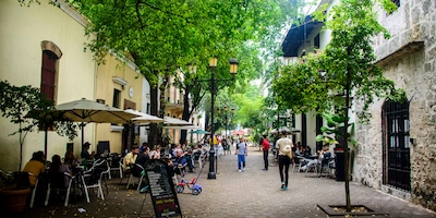 Personas sentadas descansando bajo sombrillas en la zona colonial de Santo Domingo
